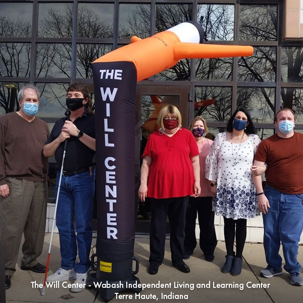 A group of people standing outside a building with a wacky inflatable